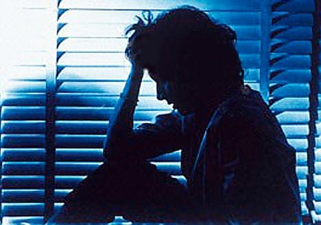 A person sitting quietly by a window in soft light, conveying the vulnerability of missing adults living with mental illness