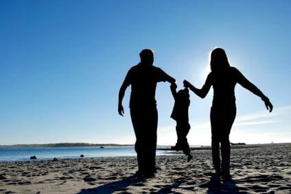 A family walking together on a beach at sunset, parents lifting their child, symbolizing hope for reuniting families
