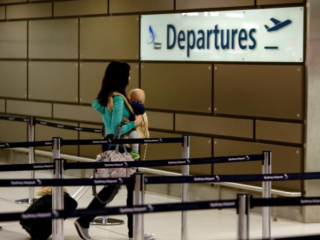 A parent carrying a child through an international airport departures hall, representing parental abduction across borders