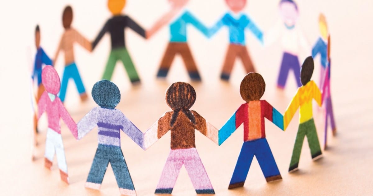 Paper figures of diverse people linked hand in hand in a circle, representing community vigilance and protection against trafficking